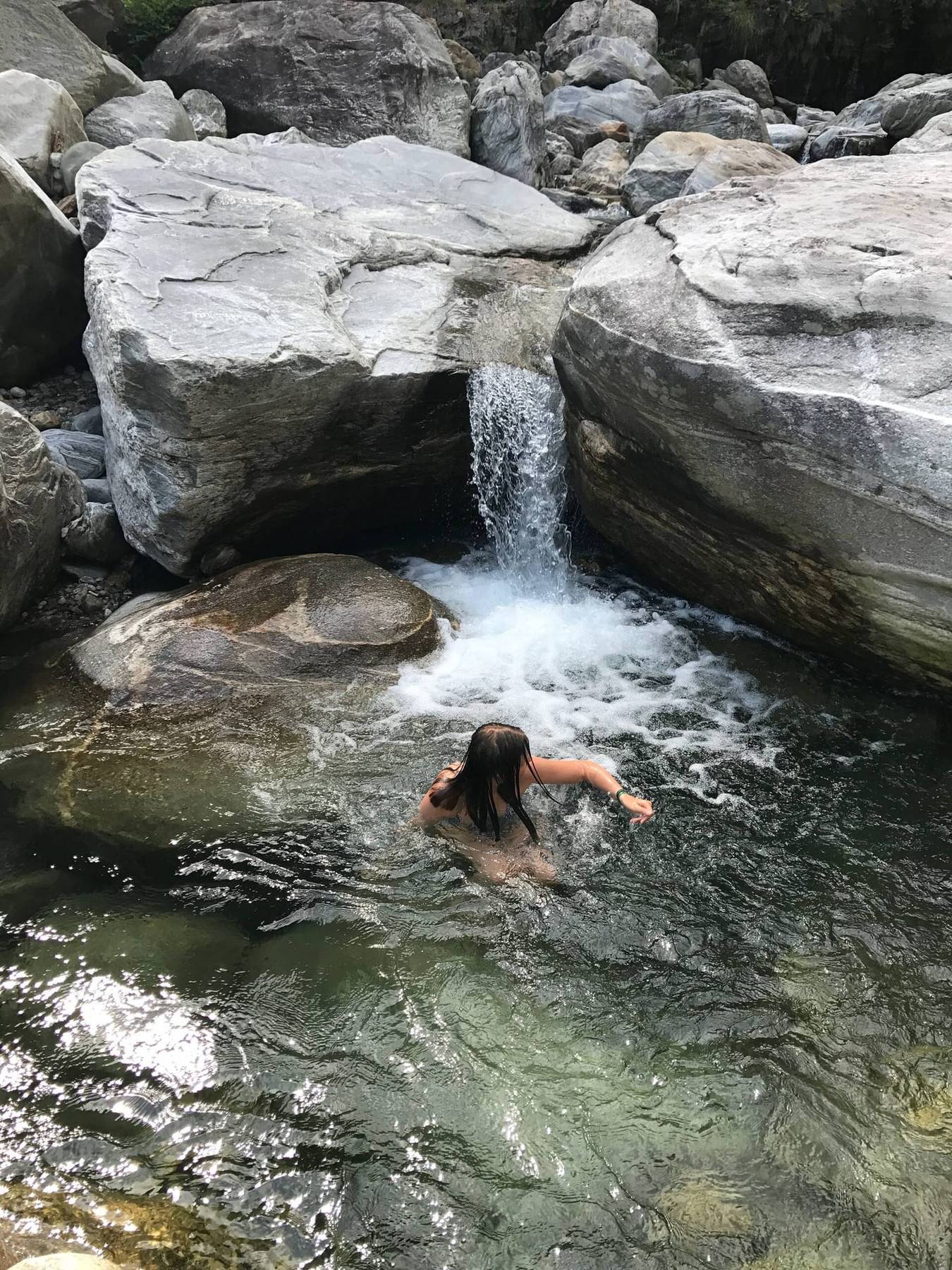 Bad i en klar elvekulp under en foss
