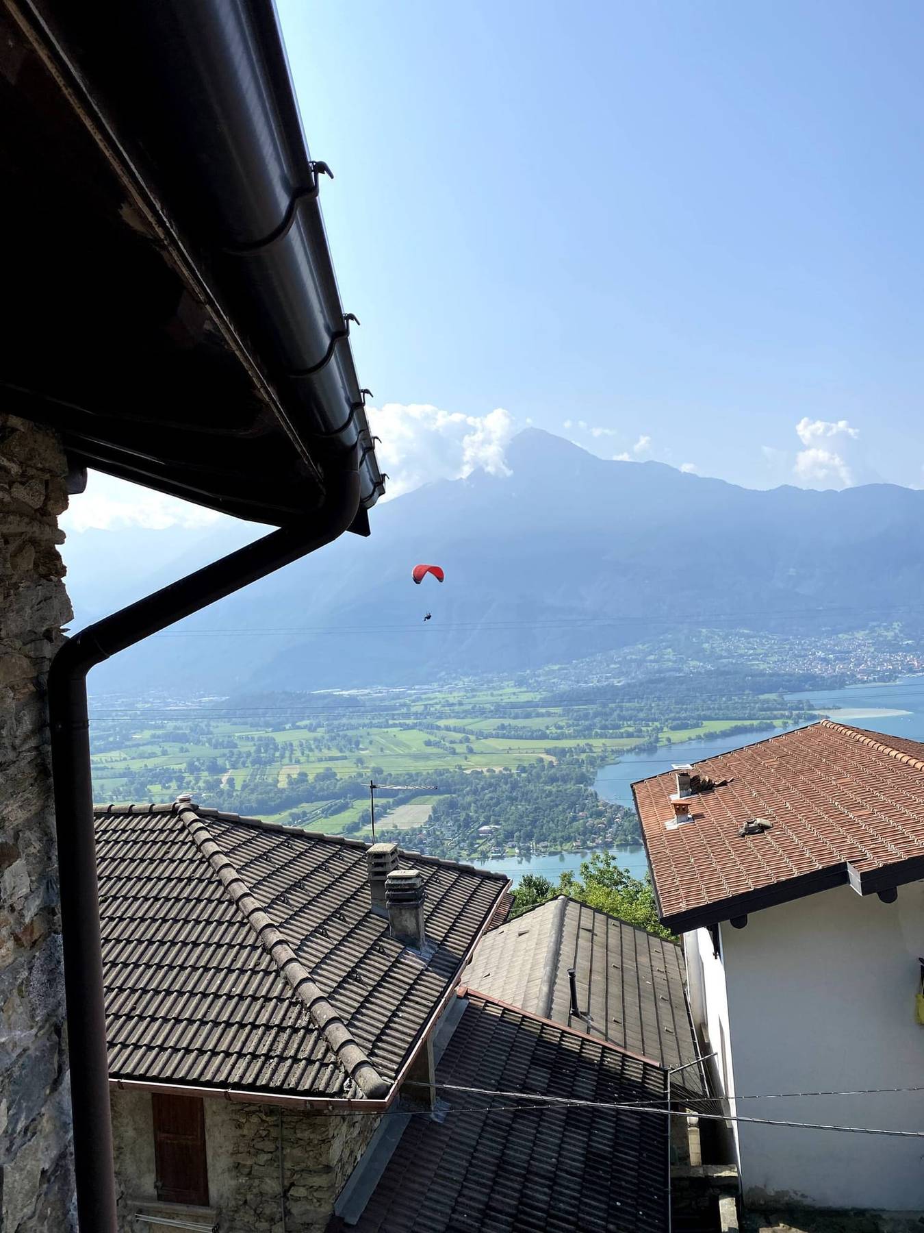 Paraglider over dalen sett fra hustakene