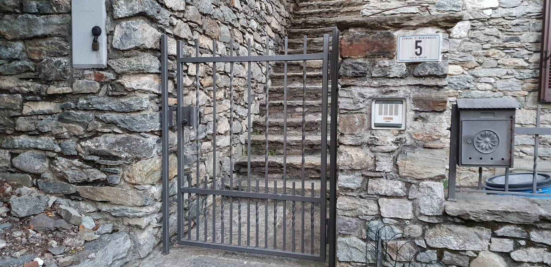 Smijernsport og steintrapp mellom gamle steinmurer i Montemezzo