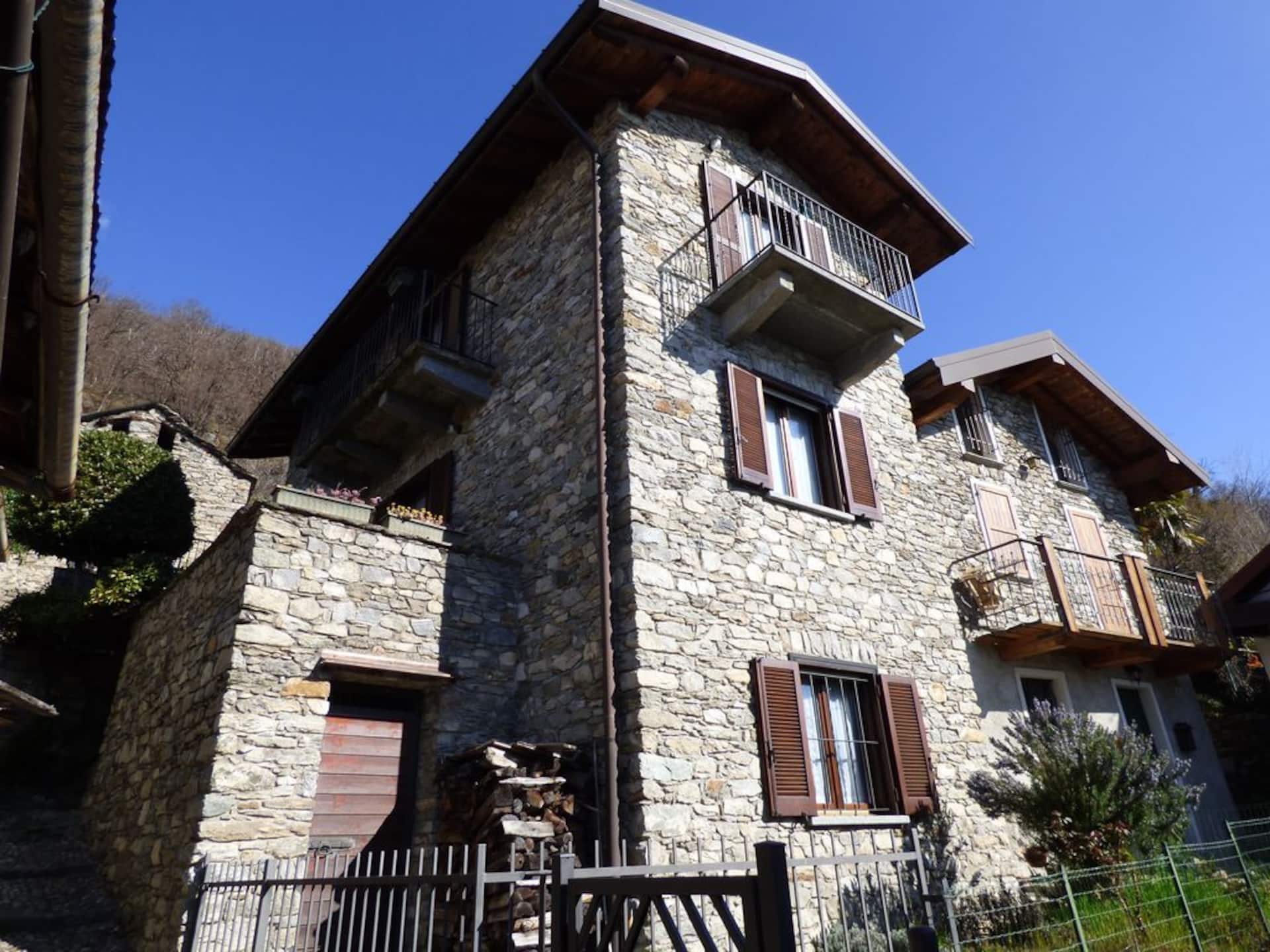 Steinhuset Villa Oppilia i Montemezzo med brune skodder og balkong