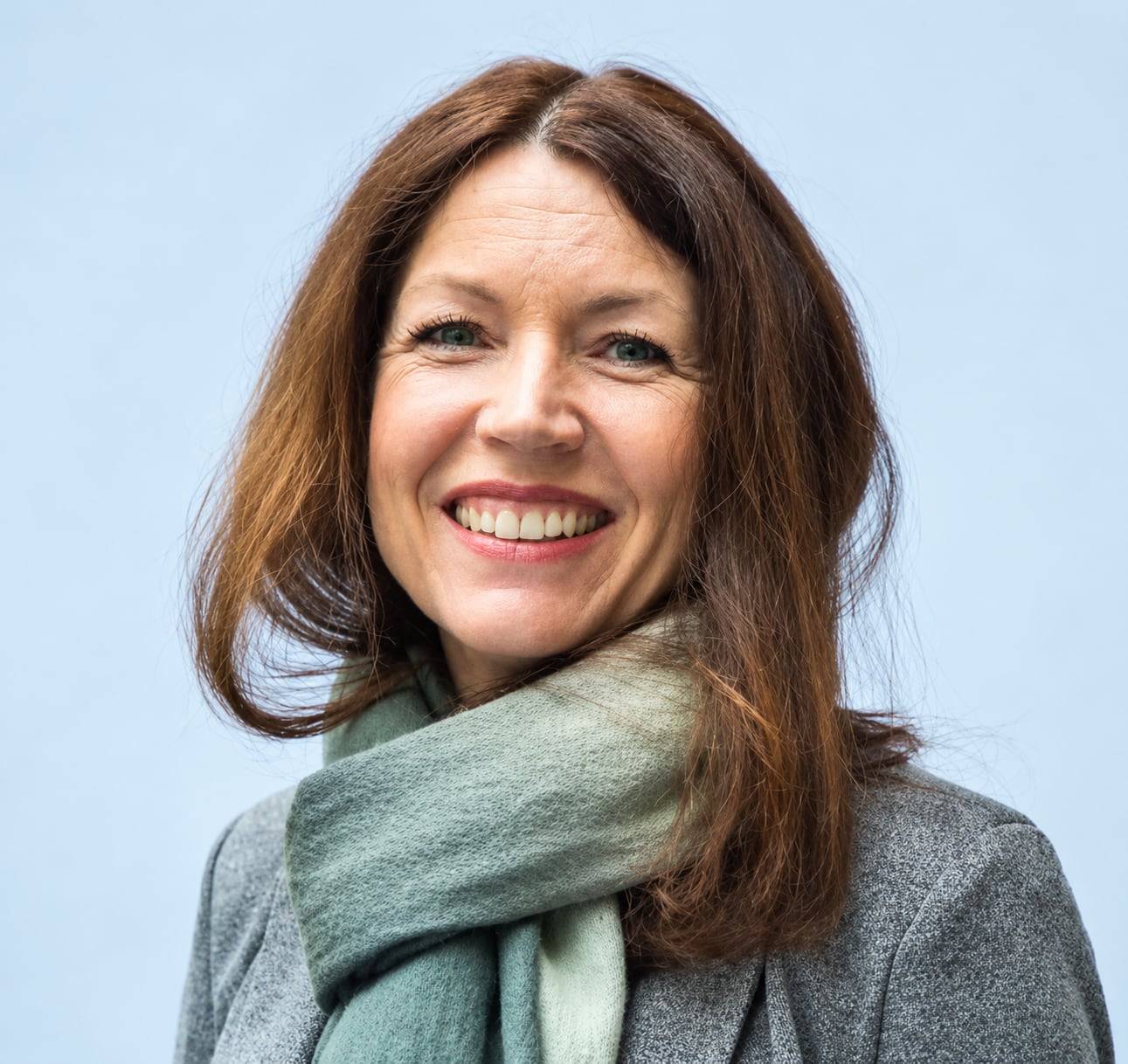 Portrett av Hilde Kristoffersen, smilende med grønt skjerf